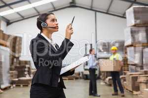 Warehouse manager wearing headset checking inventory