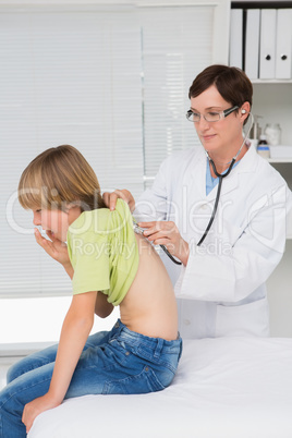 Doctor examining little boy with stethoscope