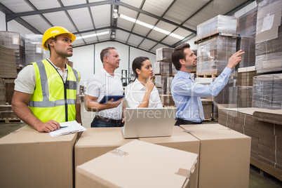 Warehouse manager pointing something to his colleagues