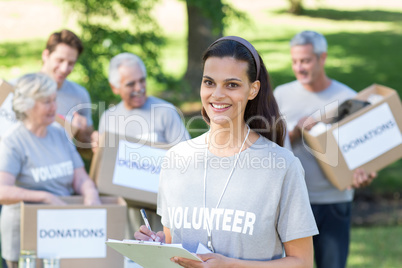 Smiling volunteer brunette writing on cipboard