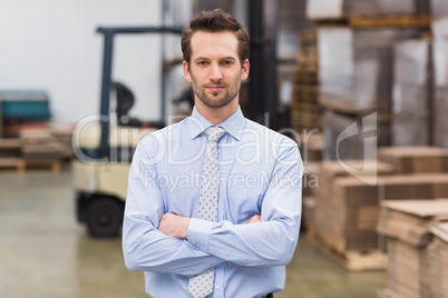 Serious manager with arms crossed in warehouse