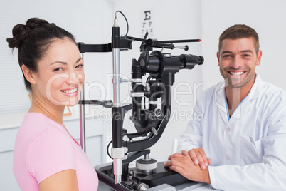 Happy optician and female patient with slit lamp