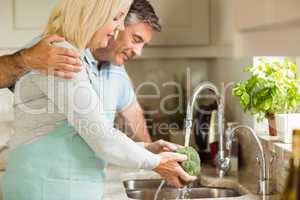 Happy mature couple washing broccoli