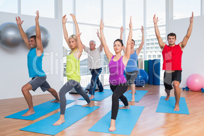 People exercising with hands raised at fitness club