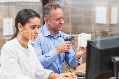 Manager scanning box while his colleague typing on laptop