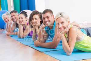 People relaxing on exercise mats at fitness studio