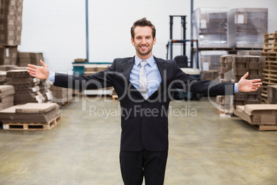 Smiling warehouse manager with hands out