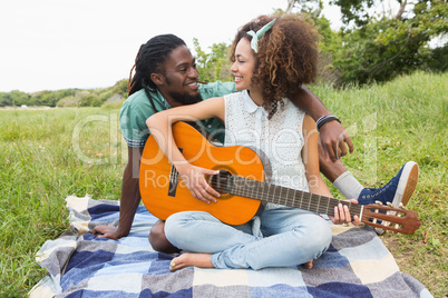 Young couple on a picnic playing guitar