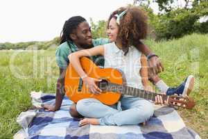 Young couple on a picnic playing guitar