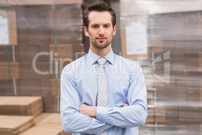 Serious manager with arms crossed in warehouse