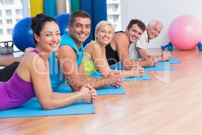 People relaxing on exercise mats in fitness studio