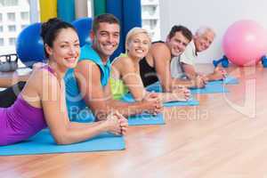 People relaxing on exercise mats in fitness studio