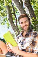 Handsome hipster reading book in park