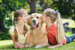 Sisters kissing their dog in the park