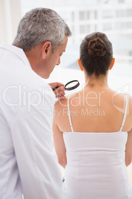 Doctor examining patient with magnifying glass