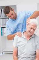 Therapist giving massage to senior male patient