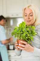 Mature blonde smiling and smelling her basil plant