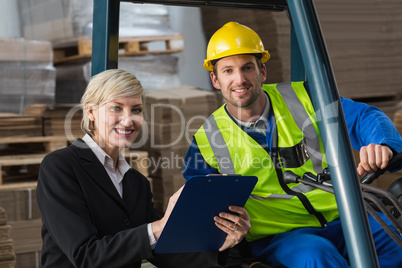 Forklift driver and manager smiling at camera