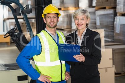 Forklift driver and his manager smiling at camera