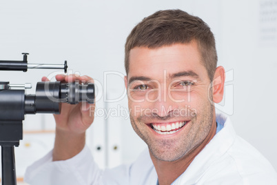 Happy optician using slit lamp in clinic