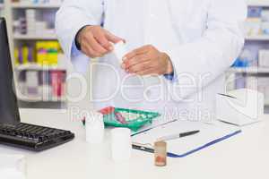 Smiling pharmacist mixing a medicine