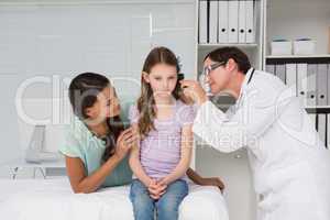 Doctor examining little girl with her mother