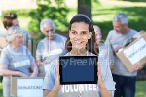 Smiling volunteer brunette showing tablet pc screen