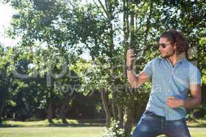 Young man playing air guitar in the park