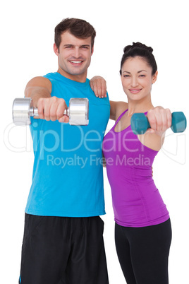 Fit man and woman lifting dumbbells