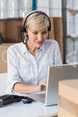 Smiling warehouse manager using laptop