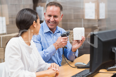 Manager scanning box while his colleague typing on laptop