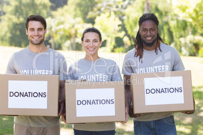 Happy volunteers with donation boxes in park