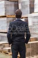 Warehouse manager in suit standing with hands in pockets
