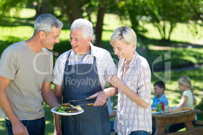 Happy couple with grandfather doing barbecue