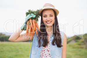 Happy brunette holding organic carrots