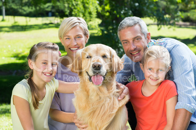 Happy family smiling at the camera with their dog