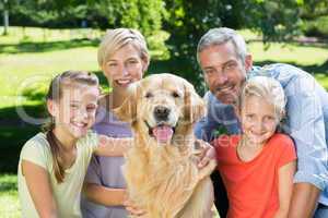 Happy family smiling at the camera with their dog