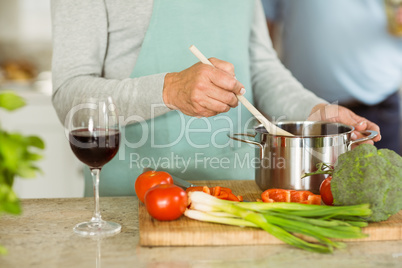 Mature couple making dinner together having red wine
