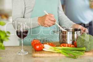 Mature couple making dinner together having red wine