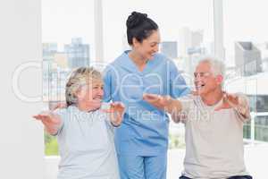 Female trainer assisting senior couple to exercise