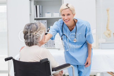 Portrait of nurse consoling patient sitting on wheelchair