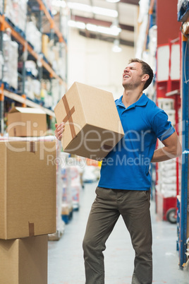 Worker with backache while lifting box in warehouse
