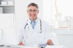 Happy male doctor reviewing documents at table