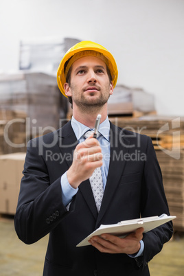 Warehouse manager wearing hard hat checking inventory