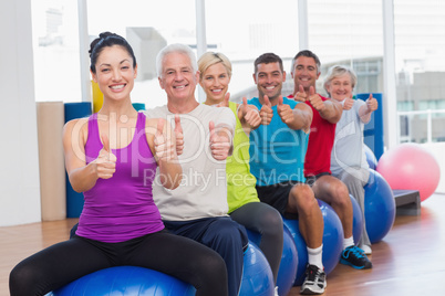 People sitting on exercising balls gesturing thumbs up