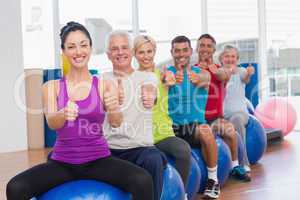 People sitting on exercising balls gesturing thumbs up
