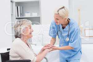 Nurse holding senior patients hands in clinic