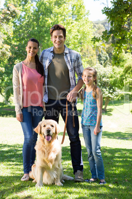 Happy family walking their dog in the park