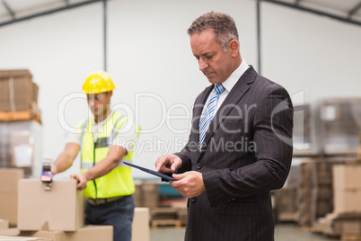 Boss using digital tablet in warehouse