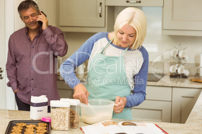 Happy blonde preparing dough with husband behind